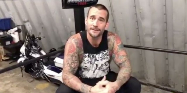 CM Punk retrocede dentro de un ring de lucha libre antes de su aparición Starrcast III