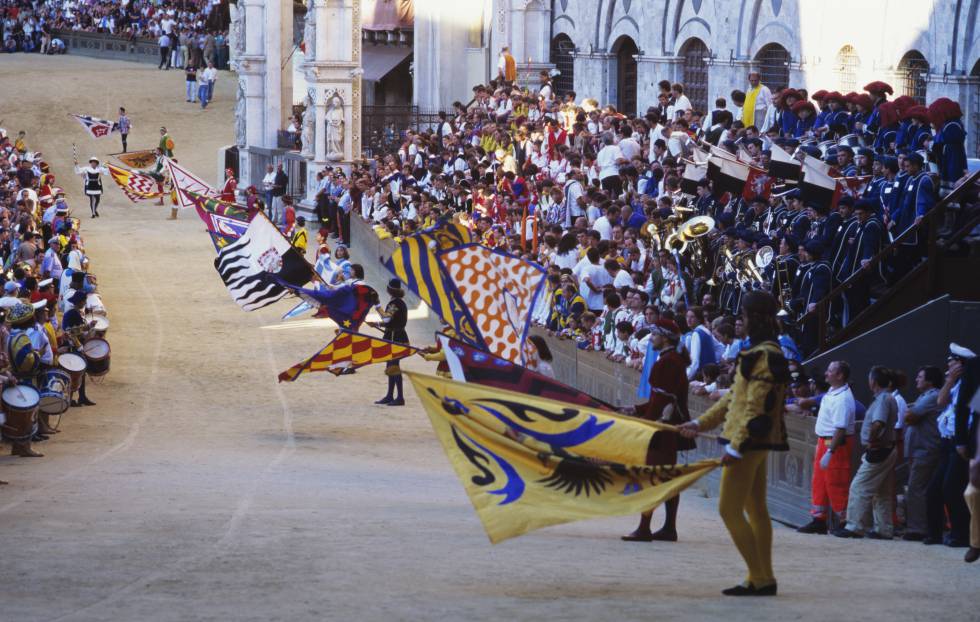 Despliegue de enormes banderas poco antes del comienzo de la carrera de caballos de Palio de Siena.