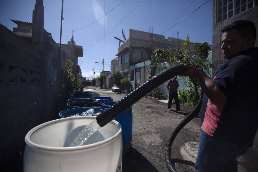 Un hombre rellena un contenedor para almacenar agua en la Alcaldía de Iztapalapa en la Ciudad de México.