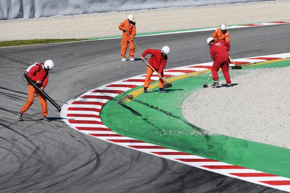 Los operarios del Circuit, limpiando las piedras que dejó el coche de Vettel en el asfalto