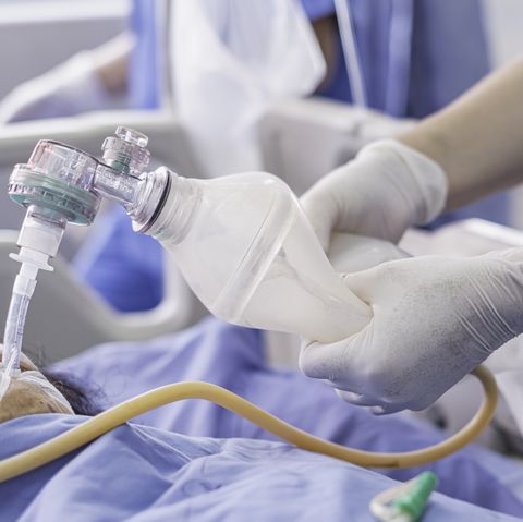 Médico sosteniendo la bolsa de oxígeno ambu sobre el paciente que recibe oxígeno al paciente mediante un tubo de intubación en la UCI / sala de emergencias