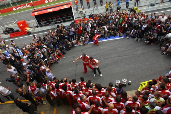 El equipo Ferrari celebra la victoria de Alonso en el pit lane haciendo un corrillo.