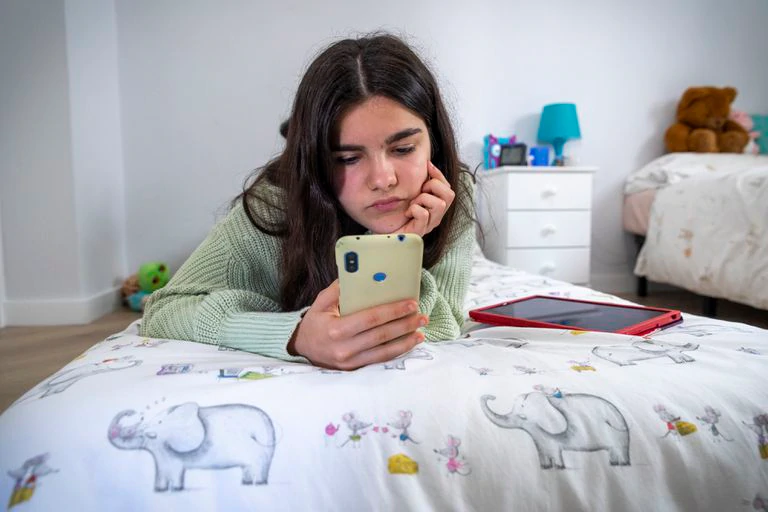 Una adolescente durante el confinamiento trastea con el móvil en su habitación.