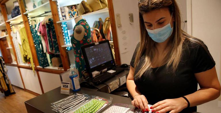 La encargada de una tienda de ropa en Barcelona ordena mascarillas en el mostrador.