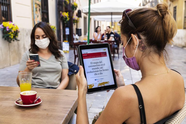 Una lectora consulta EL PAÍS en su tableta en una terraza de Valencia.