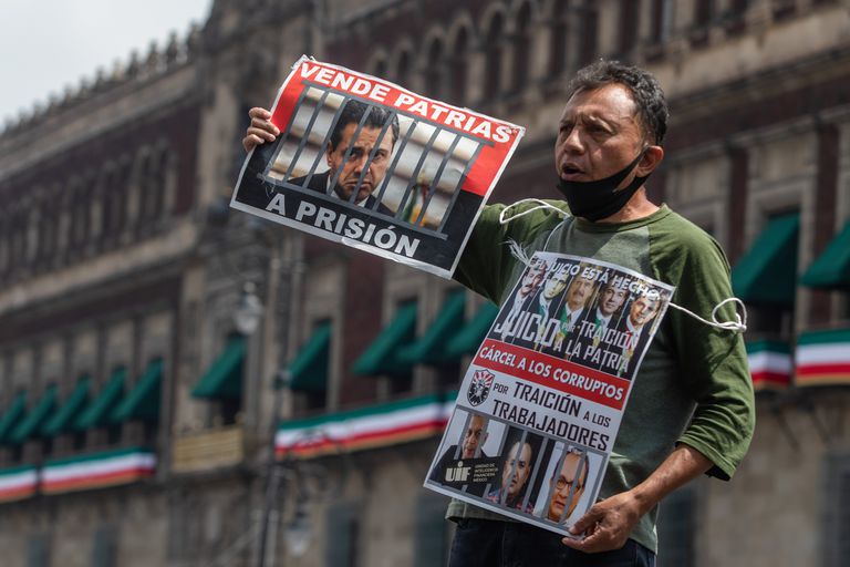 Un ciudadano sostiene imágenes de ex presidentes frente al Palacio Nacional durante la recolección de firmas para enjuiciarlos.
