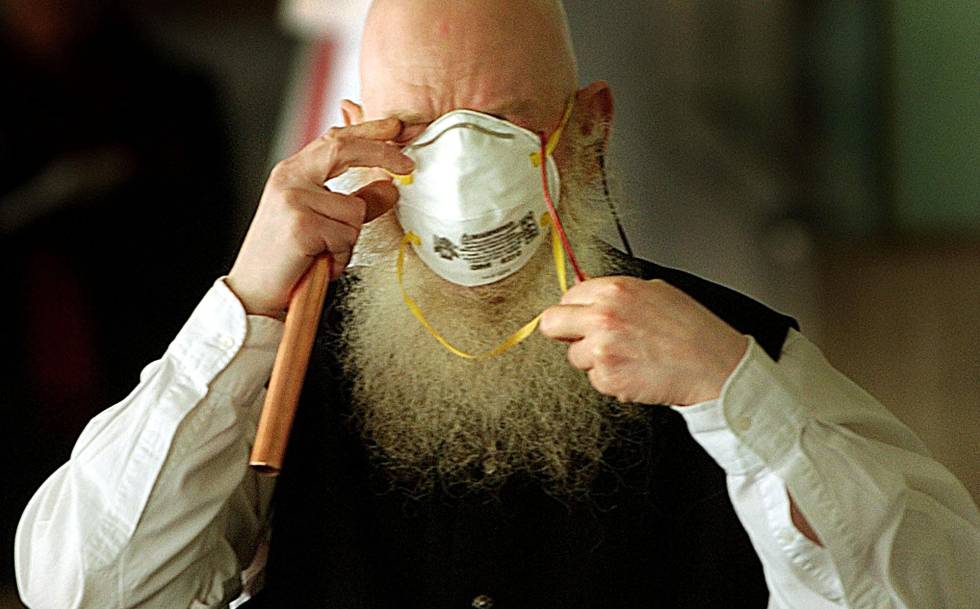Un empleado de un hospital de Toronto se pelea con su mascarilla durante la epidemia de SARS en 2003.