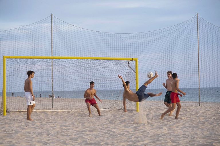 Unos jóvenes juegan al fútbol en la playa de la Victoria en Cádiz, este lunes.