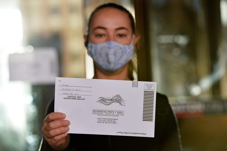 Una mujer sostiene una papeleta para votar por correo en las primarias de Massachusetts, el 1 de septiembre de 2020.