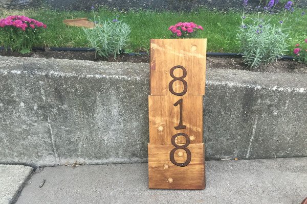 Un letrero de madera hecho a mano con números de direcciones de casas. 