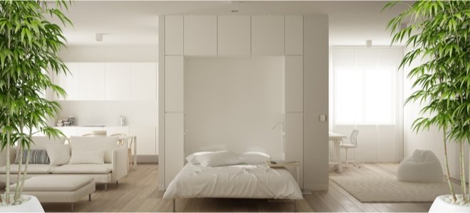 Cama de pared blanca en medio de una habitación blanca abierta