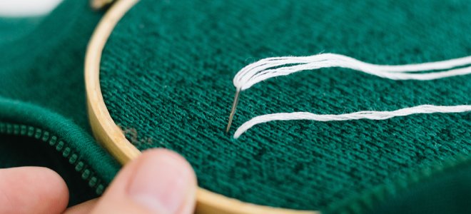 Proyecto de bordado de ropa: anillo que sujeta la tela desde la parte posterior con una aguja que pone hilo