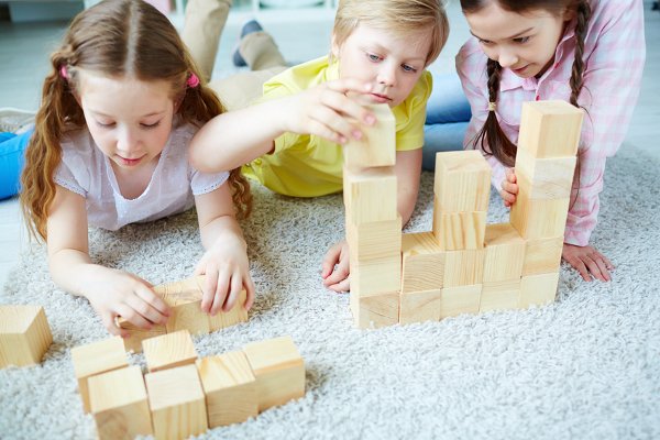 Varios niños jugando con bloques de madera en el suelo. 