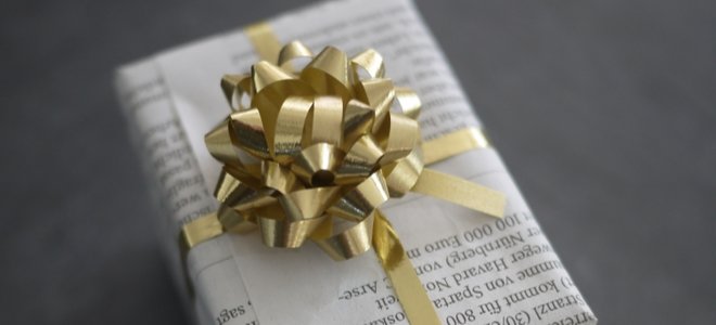 un regalo envuelto en periódico con cinta dorada y lazo