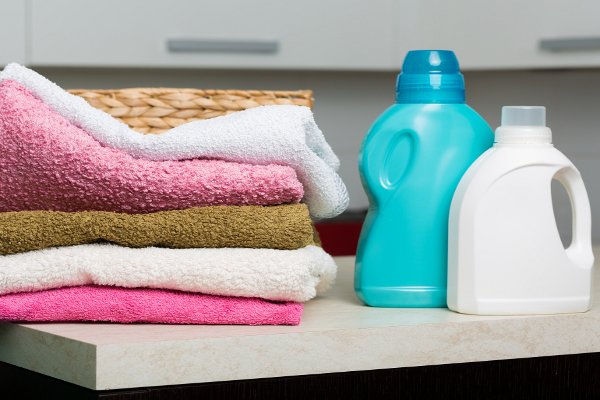 Una pila de toallas y un par de botellas de detergente para ropa. 