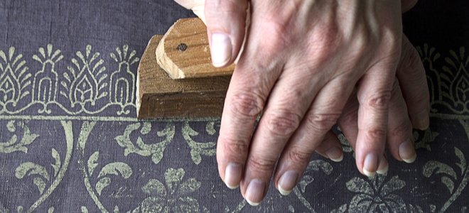 dos manos presionando un sello estampado sobre la tela