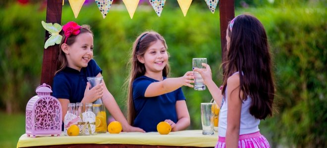niñas felices en un puesto de limonada