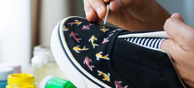 mano pintando un patrón de pez en zapatos negros