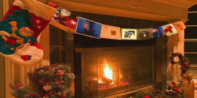 Una guirnalda de tarjetas navideñas colgando frente a una chimenea. 
