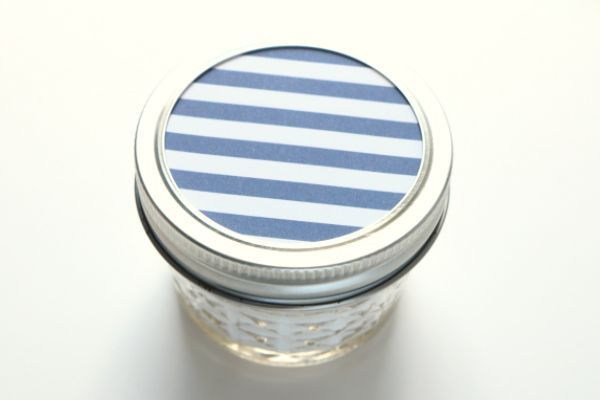 Un frasco de conservas con papel rayado azul y blanco como tapa. 