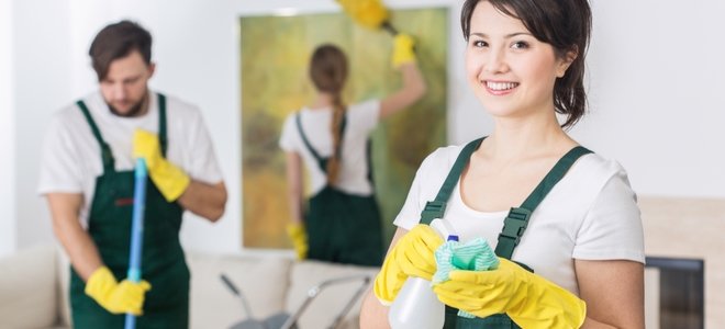 trabajadores de limpieza de la casa con guantes y delantales limpiando una habitación