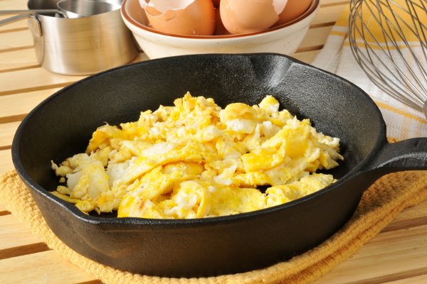 Una sartén de hierro fundido con huevos revueltos. 