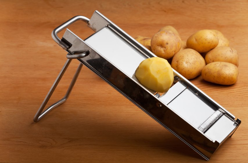 Una cortadora de mandolina con patatas. 