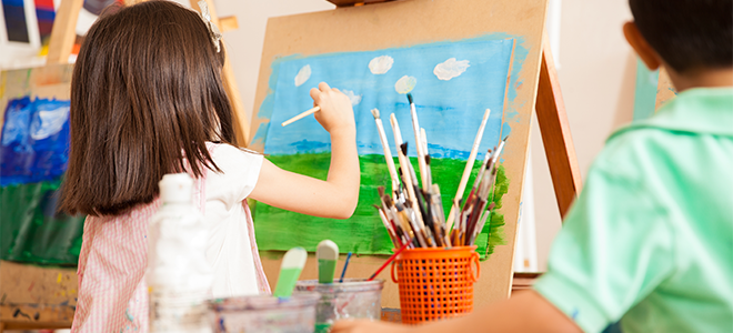 Una niña pintando una escena al aire libre en clase.