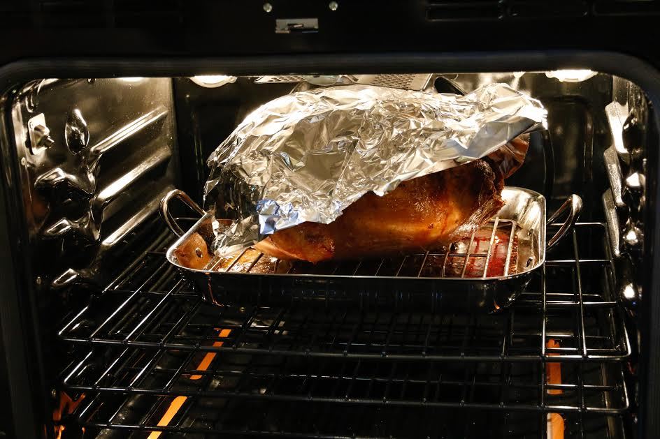 Un pavo que se cocina en un horno con papel de aluminio encima. 