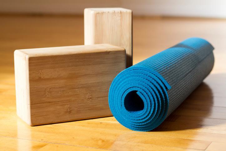 Una estera de yoga azul y dos bloques de madera para yoga. 