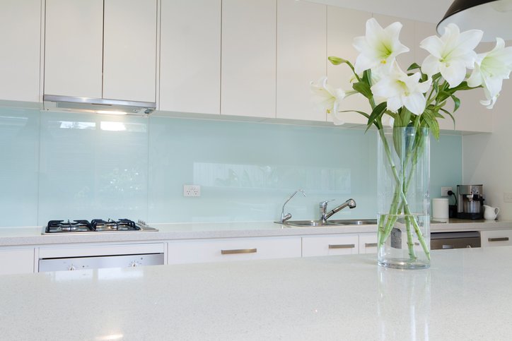 Una cocina limpia y minimalista con un jarrón de flores en la encimera. 