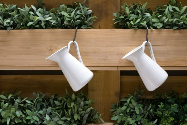 Cajas de plantas con ganchos y jarras blancas. 