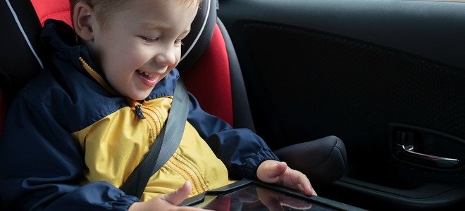 Un niño divirtiéndose con una tableta en un coche. 