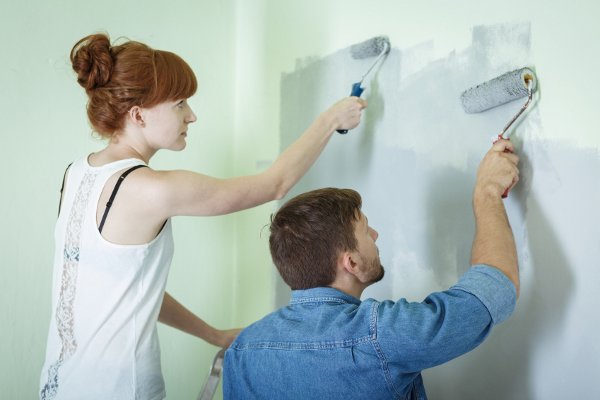 Una pareja pintando una pared juntos. 
