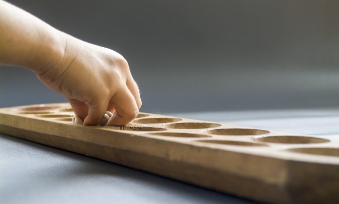 mano jugando manaca en un tablero de juego de madera