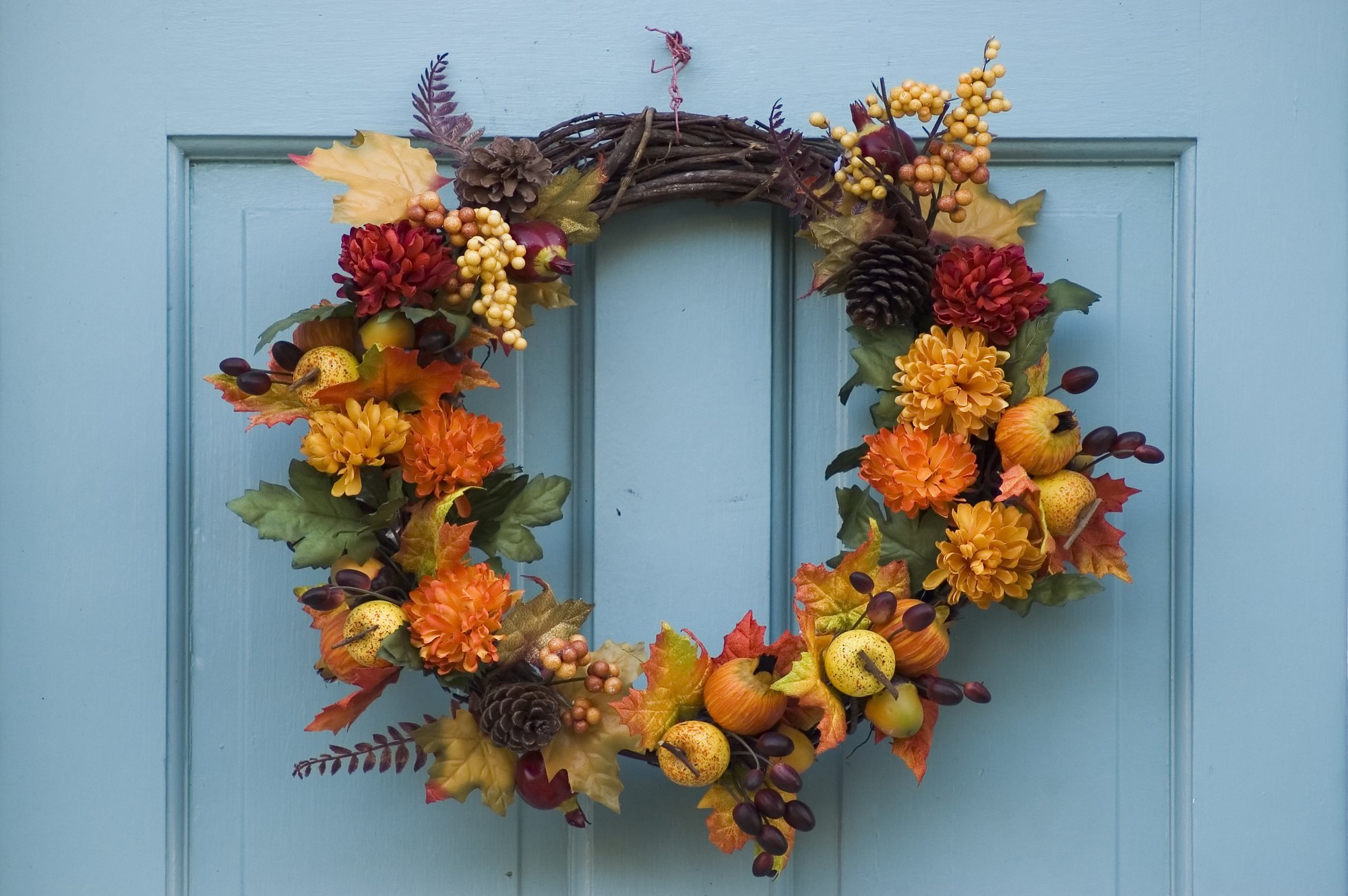 Una corona de otoño en una puerta azul claro.