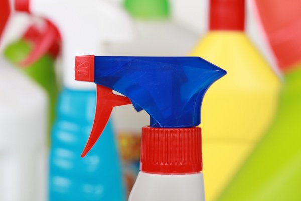 Una imagen de primer plano de una botella de spray con otros productos de limpieza en el fondo.
