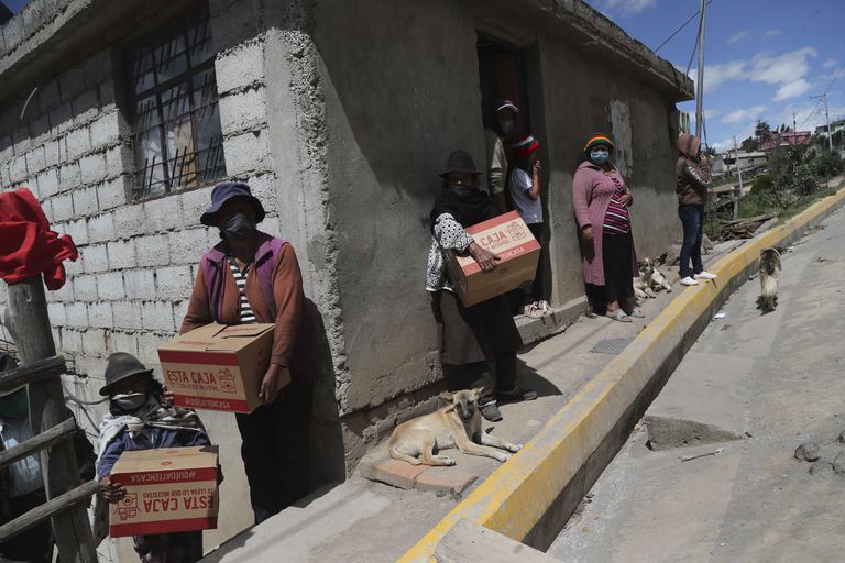 Un grupo de mujeres y niños reciben cajas con ayuda de emergencia para sobrellevar el confinamiento, a las afueras de Quito (Ecuador).
