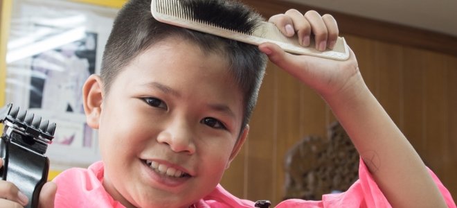 niño cortando su propio cabello con un peine y una maquinilla de afeitar eléctrica