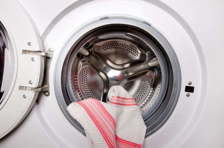 Una secadora con una toalla a rayas blancas colgando en la parte delantera. 