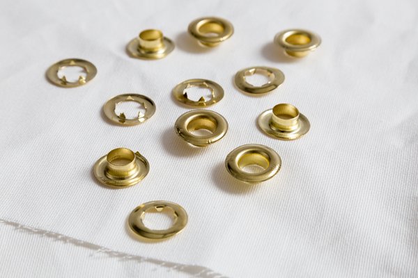 Un montón de ojales de oro sobre una tela blanca. 