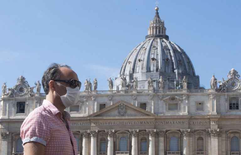Un turista pasea con mascarilla por delante de la plaza de San Pedro, en el Vaticano.