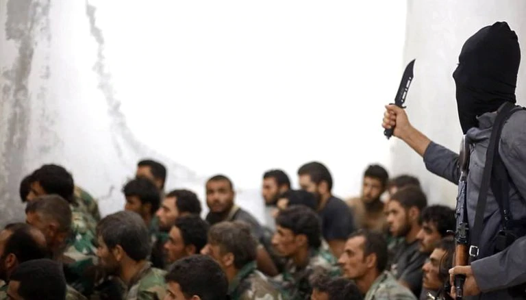 Un soldado del ISIS encapuchado vigila a un grupo de soldados sirios capturados en Raqqa en agosto de 2014.