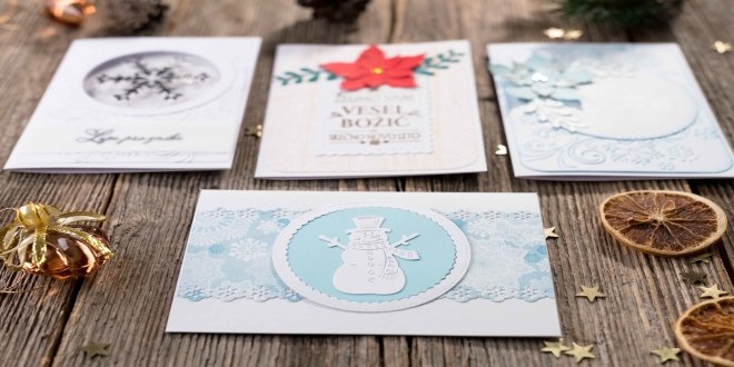 Cuatro tarjetas de Navidad sobre una mesa de madera rústica. 