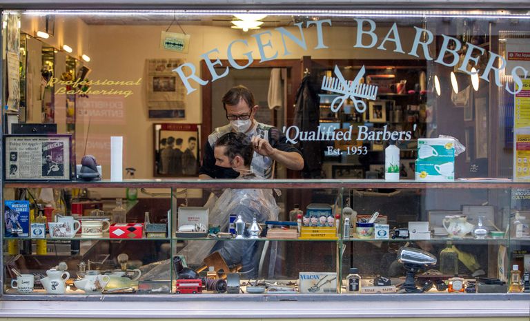 Un peluquero con mascarilla atiende a un cliente en Dublín este lunes.