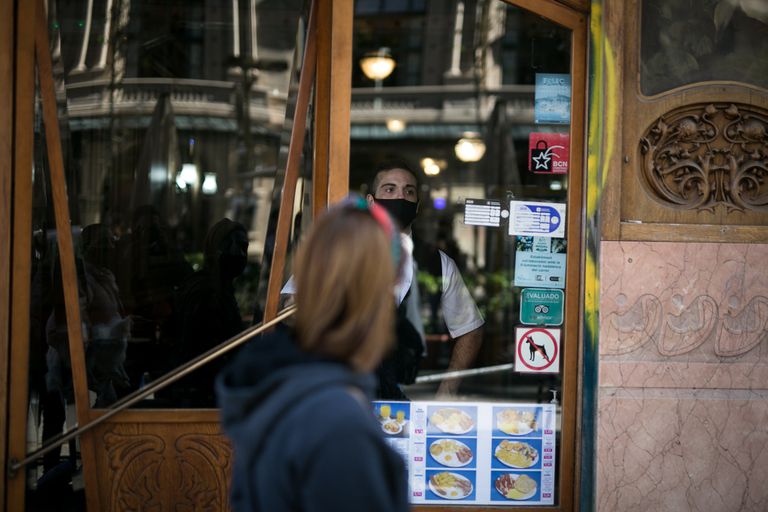 Un camarero del Café de la Ópera en Barcelona mira a través del cristal de la puerta.