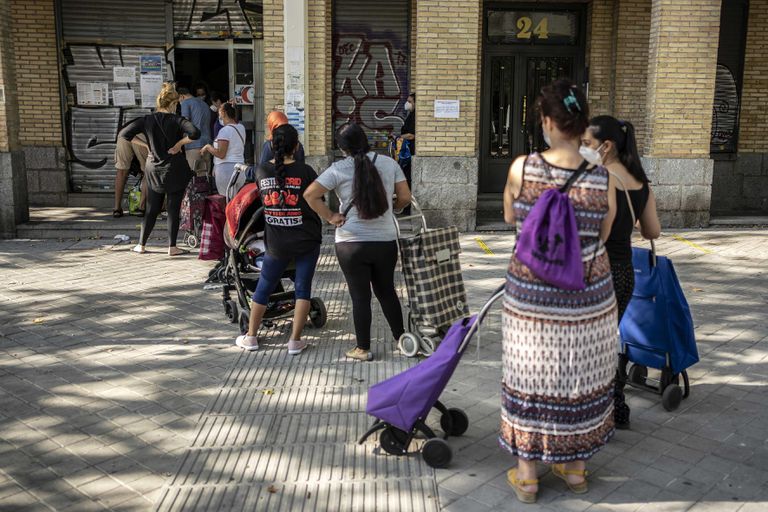 Un grupo de personas hace cola en el banco de alimentos Gran Avenida 24, en el barrio de Orcasitas, Madrid.