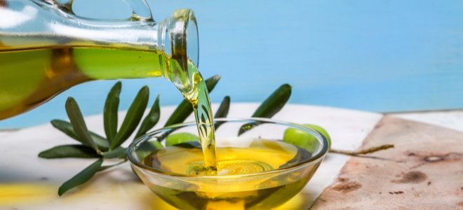Jarra de vidrio vertiendo aceite de oliva en un plato