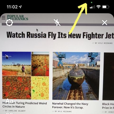 una flecha amarilla apunta a la luz indicadora de grabación verde en la pantalla del iphone del autor mientras usa la aplicación de instagram, esto significa que la aplicación está usando la cámara
