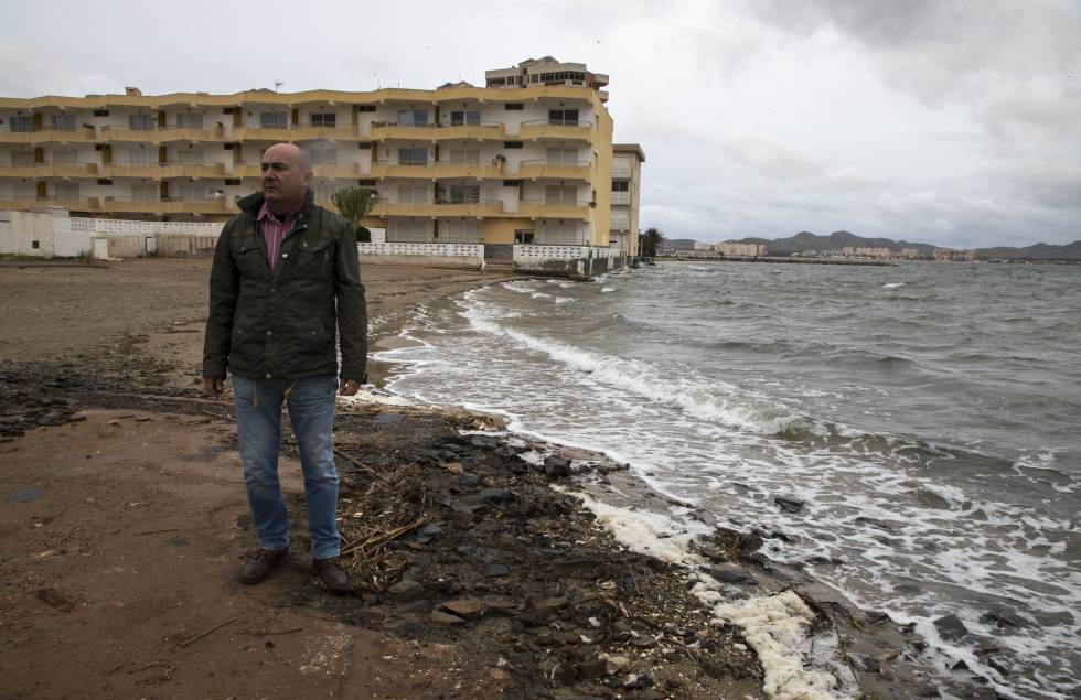 Javier Caballero posa junto al edificio en el que vive, al que ya ha llegado el Mar Menor.